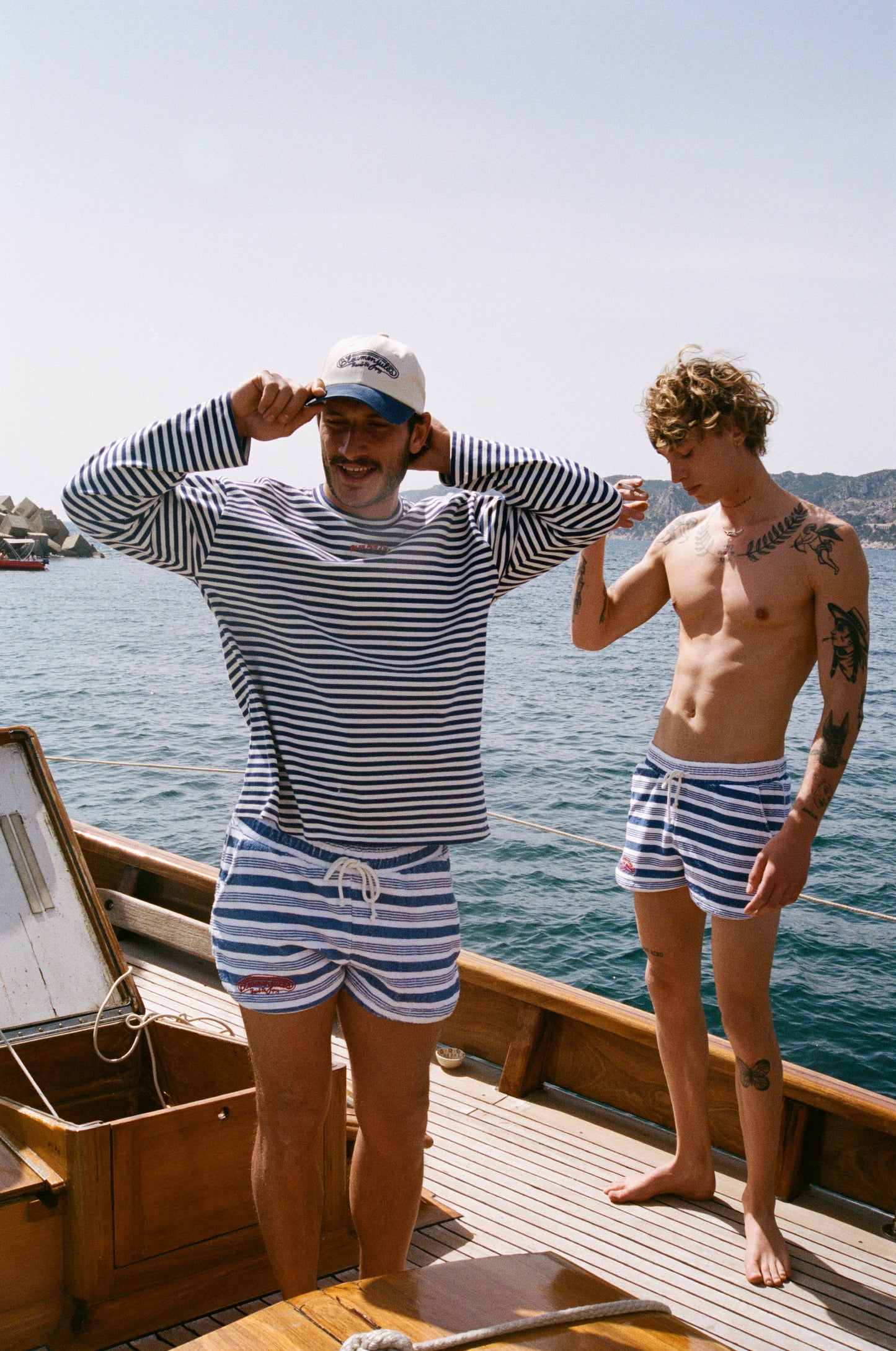 Deux hommes sur un bateau portent la casquette Popcorn beige et bleu marine avec broderie Bleumonjules Saint-Tropez