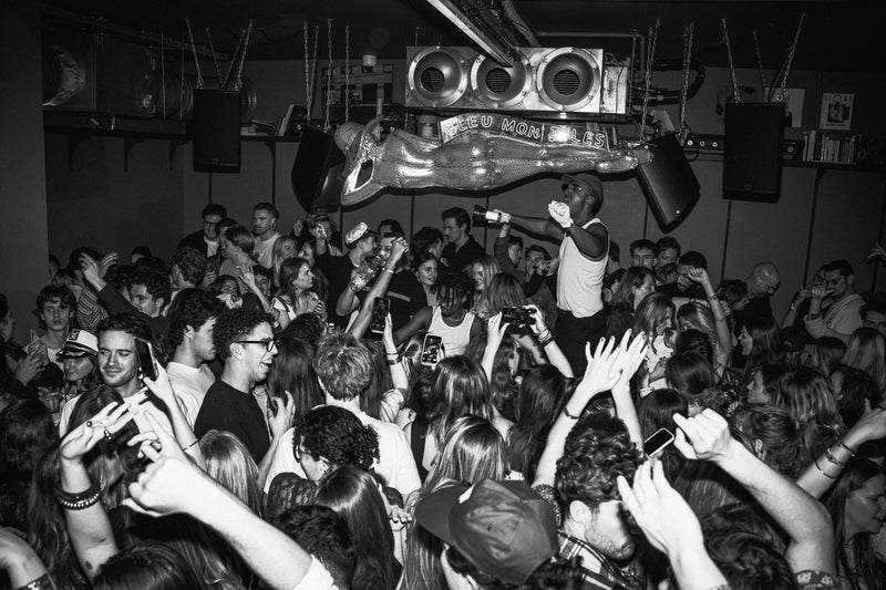 Foule en délire lors d'un concert en discothèque avec DJ sur estrade et système audio trois ventilateurs