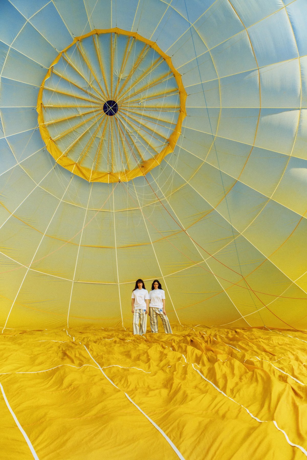 Deux femmes en blanc dans une montgolfière jaune et blanche gonflée, vue intérieure de l'enveloppe avec structure radiale