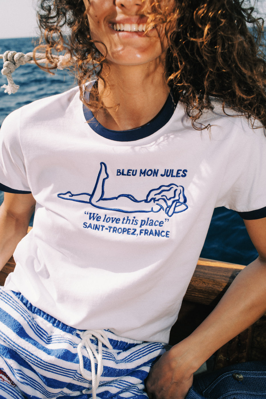 Femme en t-shirt blanc Bleu Mon Jules avec marinière rayée bleu et blanc, shorts rayés bleu blanc absorbants style cabine plage Saint-Tropez
