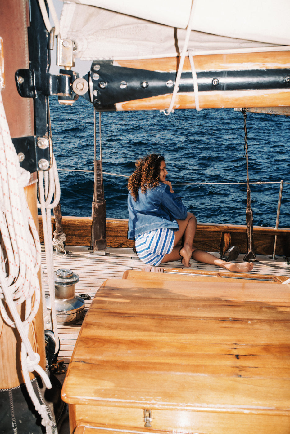 Femme portant un short rayé bleu et blanc en éponge méditerranéenne, assise sur le pont d'un voilier